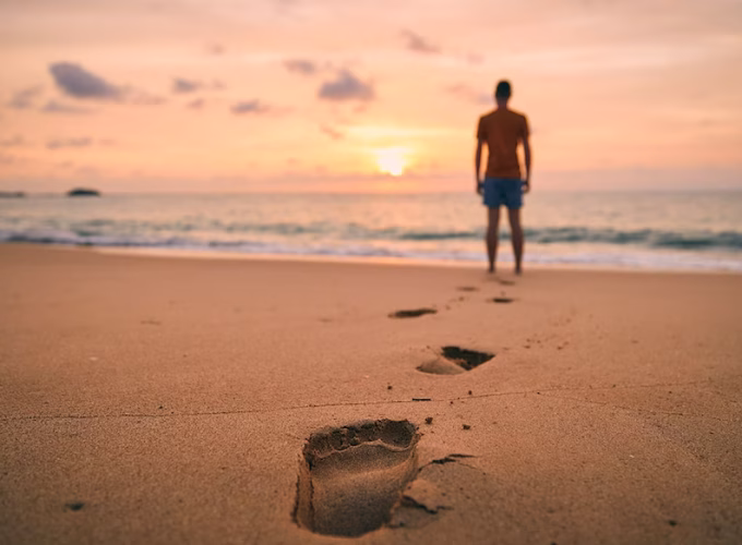 Lonely man walking along beach istock photo